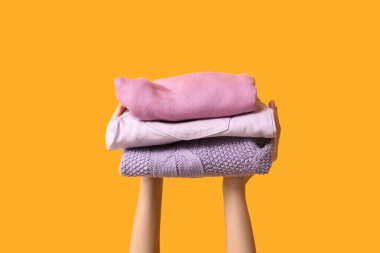 Sarı arka planda kalın giysileri olan kadın elleri.