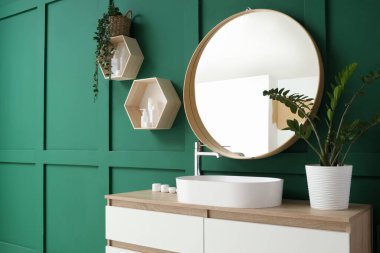 Lavabosu, aynası ve rafları olan bir banyo.