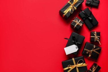 Kırmızı arka planda boş karton etiketli hediye kutuları. Kara Cuma indirimi