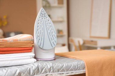 Evdeki ütü masasında bir yığın temiz çarşaf ve ütü var.