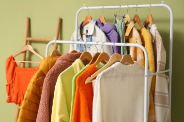 Yeşil duvarın yanında sonbahar giysileriyle raflar