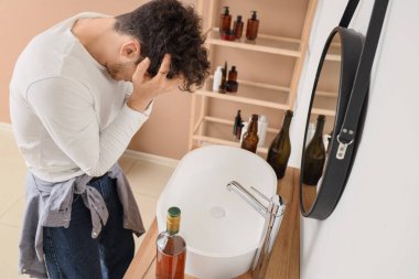 Banyoda akşamdan kalma genç bir adam. Alkolizm kavramı