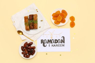 Tebrik kartı, tarihler, baklava ve sarı arka planda kurutulmuş kayısılar. Ramazan kutlaması