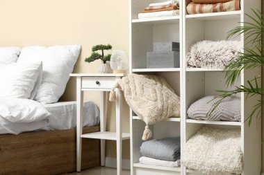 Yatak odasında temiz çarşaflar, kutular ve ekoseli raflar.