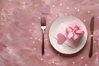 Zarflı güzel bir masa ve pembe arka planda hediye kutusu. Sevgililer Günü kutlaması