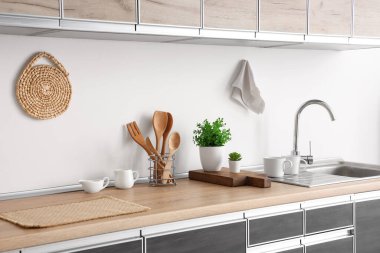 Mutfaktaki masanın yanındaki beyaz duvarın yanında ev bitkileri ve bulaşık malzemeleri.