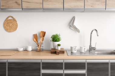 Mutfaktaki masanın yanındaki beyaz duvarın yanında ev bitkileri ve bulaşık malzemeleri.