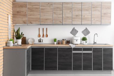 Modern mutfağın içinde siyah tezgah, çoklu mutfak ve çatal bıçaklar var.