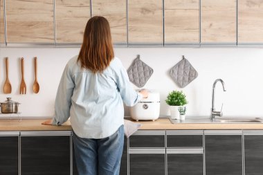 Evdeki mutfak tezgahlarının yanındaki genç kadın.