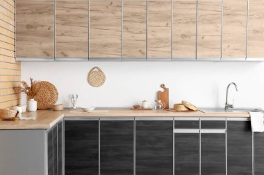 Beyaz duvarın yanında siyah tezgah ve çatal bıçakları olan modern mutfağın içinde.