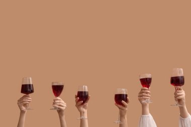 Bej arka planda kırmızı şarap kadehleriyle kadın elleri