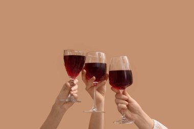 Bej arka planda kırmızı şarap kadehleriyle kadın elleri