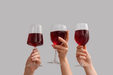 Beyaz arka planda kırmızı şarap kadehleri olan kadın eller.