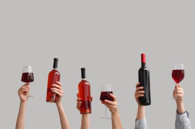 Beyaz arka planda şişe ve kırmızı şarap kadehleriyle kadın elleri.