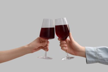 Kadın elleri beyaz arka planda kırmızı şarap kadehleriyle şıngırdıyor