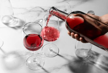 Genç bir kadın mermer zemin üzerine kırmızı şarap döküyor.