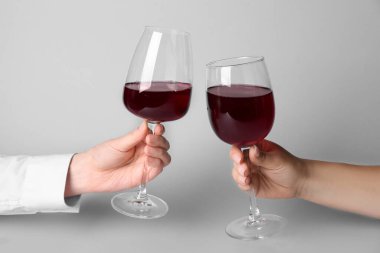 Beyaz arka planda kırmızı şarap kadehleri olan kadın eller.