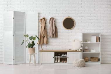 Koridorun iç tarafındaki beyaz tuğla duvarın yanında katlanan ekran ve raf ünitesi