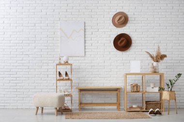 Ayakkabıları, rafları ve koridorun iç tarafındaki beyaz tuğla duvarın yanındaki bankı temsil ediyor.