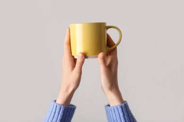 Gri arka planda seramik kupalı kadın elleri, yakın plan.