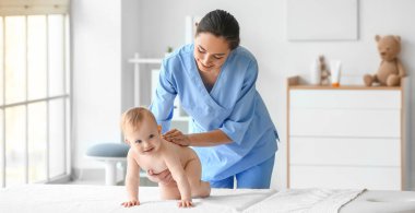 Tıp merkezinde şirin bir bebekle çalışan masaj terapisti.