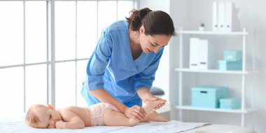 Tıp merkezinde şirin bir bebekle çalışan masaj terapisti.