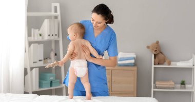 Tıp merkezinde şirin bir bebekle çalışan masaj terapisti.