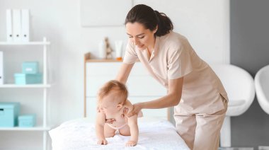 Tıp merkezinde şirin bir bebekle çalışan masaj terapisti.