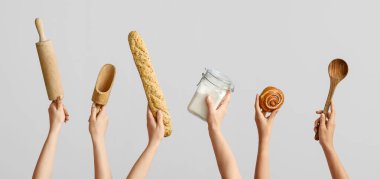 Gri zemin üzerinde fırın kapları, un ve hamur işi olan eller