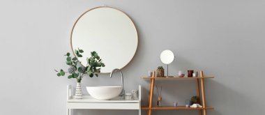 Modern lavabosu, aynası ve okaliptüs dalları olan şık bir banyo.