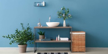 Modern lavabosu, çamaşır sepeti ve okaliptüs dalları olan şık bir banyo.