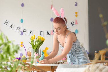 Mutfakta Paskalya yumurtası ve tavşanları olan genç bir kadın.