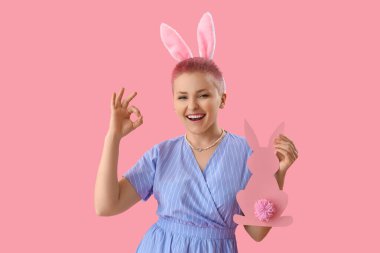 Paskalya tavşanlı genç kadın pembe arka planda iyi görünüyor.
