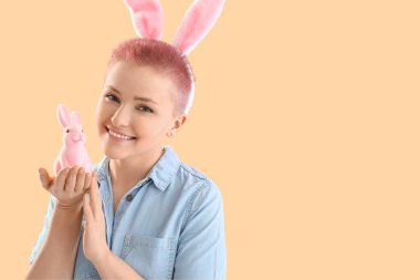 Tavşan kulaklı genç kadın ve bej arka planda Paskalya tavşanı, yakın plan.