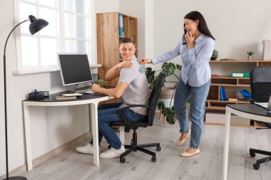 Meslektaşının sırtına kağıt balık yapıştıran genç bir kadın. 1 Nisan Kutlaması