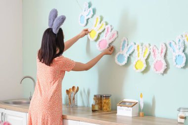 Tavşan kulaklı güzel genç bir kadın mutfağı dekore ediyor. Paskalya kutlaması