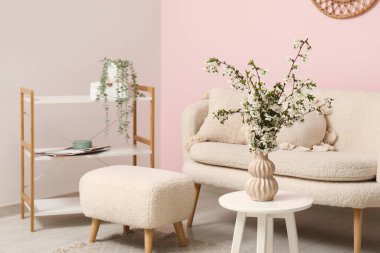 Oturma odasının içinde vazodaki dallar, puf ve rahat kanepe.