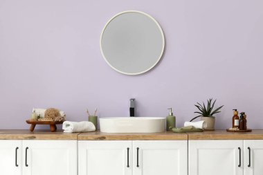 Ayna, banyo malzemesi ve lavabo olan çekmeceler. Banyonun iç tarafındaki leylak duvarın yanında.