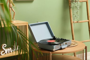 Odadaki sehpanın üzerinde disk ve ev dekorasyonu olan bir plak çalar.