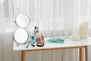 Dekoratif kozmetik ürünleri, aynalar ve mumlarla giyinme masası.
