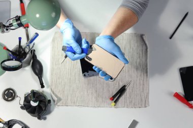 Servis merkezinde cep telefonunu tamir eden erkek teknisyen.