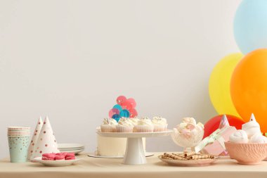 Beyaz duvara karşı doğum günü partisi için farklı şekerlemeler ve balonlar.