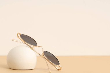 Şık güneş gözlükleri ve bej arka planda sıva podyumu