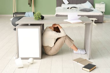 Yatak odasında deprem sırasında masanın altında saklanan kadın.