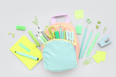 Gri arka planda farklı kırtasiye malzemesi ve şık okul çantasına sahip kompozisyon