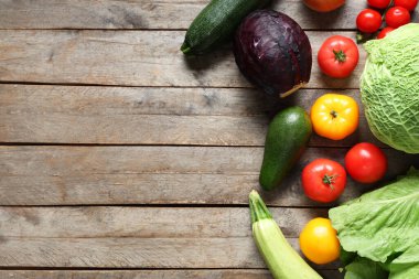 Gri ahşap arka planda farklı taze sebzeler.