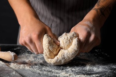Siyah arka planda taze hamur yoğuran adam, yakın plan.