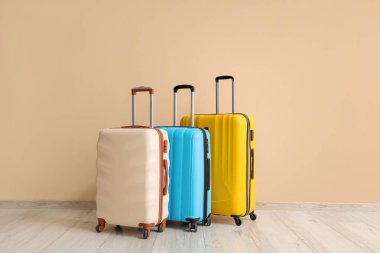 Bavullar bej duvarın yanında.