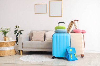Oturma odasında yastıklı ve sırt çantalı bavullar. Seyahat kavramı