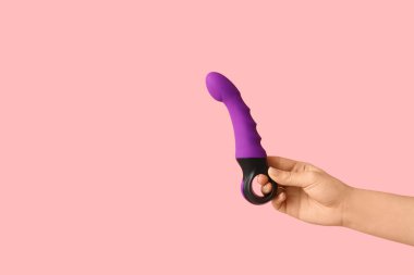 Pembe arka planda mor vibratörü olan bir kadın el.